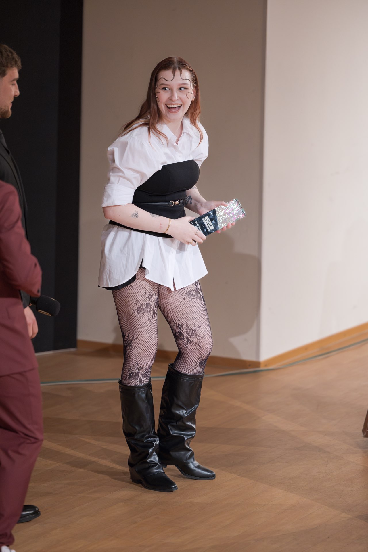 Eine Gewinnerin steht strahlend mit ihrer Trophäe auf der Bühne