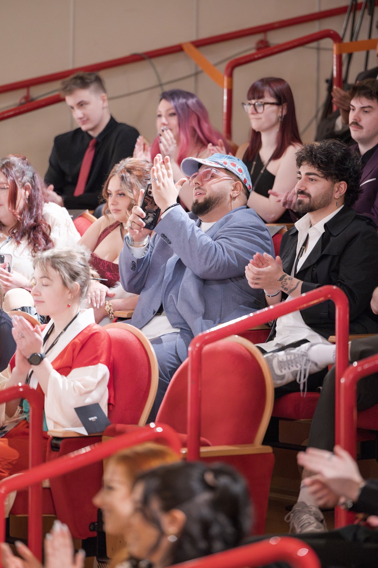Applaudierendes Publikum auf der Tribüne, ein Gast filmt mit dem Handy